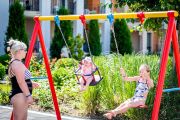 Детские качели среди зелёных насаждений на благоустроенной территории Premier Fort Beach, Святой Влас.