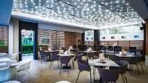 Крытая ресторанная терраса со столиками и декоративным освещением в Premier Fort Beach, Болгария.