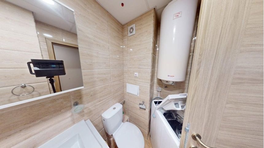 Ванная комната с унитазом, бойлером и стиральной машиной в студии Premier Fort Beach, Болгария.