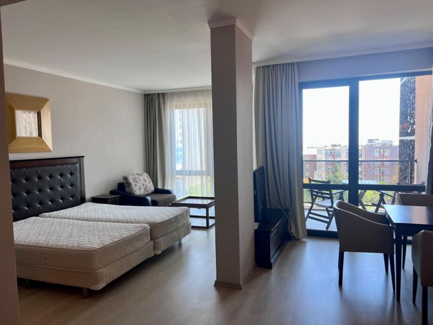 Студия 56 м² в ЖК Барсело Роял Бич — спальные места, обеденный стол и выход на балкон